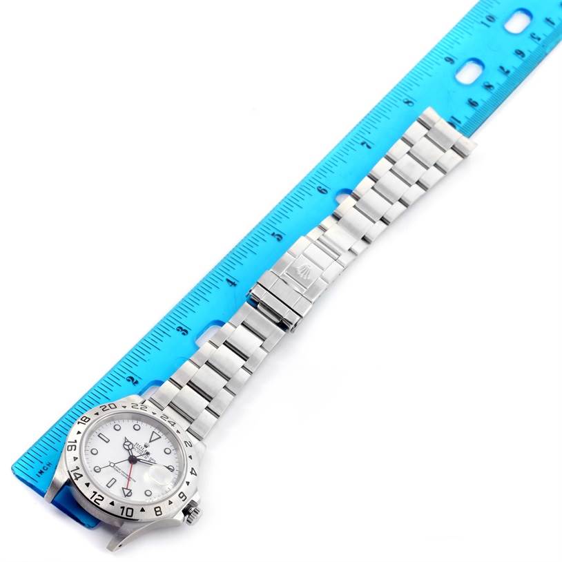 The Rolex Explorer 16570 Men's Stainless Steel White Dial 16570 Men's Stainless Steel White Dial watch is shown from a top-down angle, with its dial, bezel, and bracelet prominently displayed alongside a ruler.