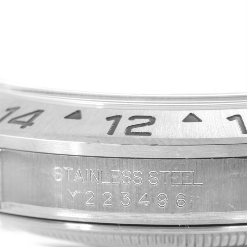 This close-up image shows the side of the bezel and case of a Rolex Explorer 16570 Men's Stainless Steel White Dial 16570 Men's Stainless Steel White Dial watch, highlighting the engraved stainless steel material and serial number.