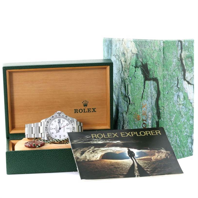 The image shows a Rolex Explorer 16570 Men's Stainless Steel White Dial 16570 Men's Stainless Steel White Dial watch, its green box, the wooden interior, a booklet, and additional watch tags.