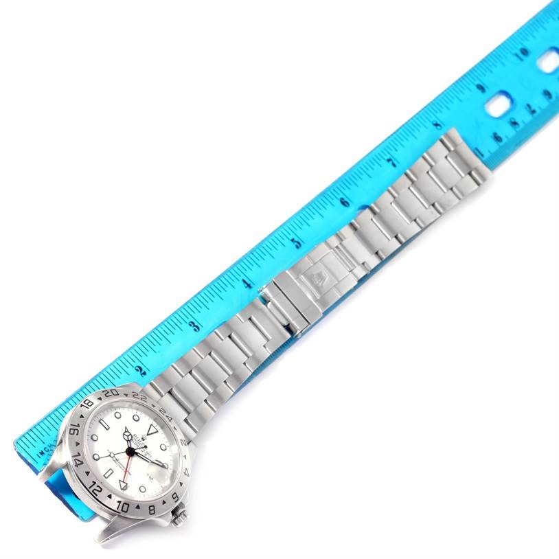 The image shows a Rolex Explorer 16570 Men's Stainless Steel White Dial 16570 Men's Stainless Steel White Dial watch laid flat next to a blue ruler, displaying the watch face and metal strap.