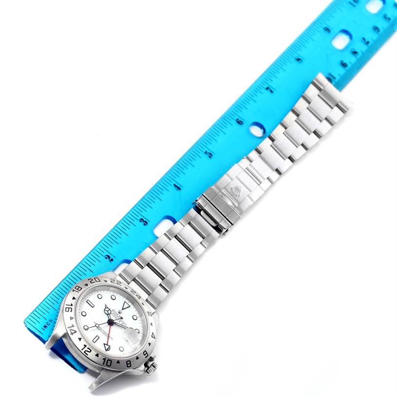 The image shows a Rolex Explorer 16570 Men's Stainless Steel White Dial 16570 Men's Stainless Steel White Dial model watch laid next to a blue ruler, displaying the face and bracelet.