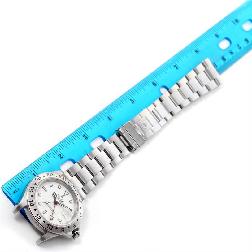 The Rolex Explorer 16570 Men's Stainless Steel White Dial 16570 Men's Stainless Steel White Dial watch is shown from a top-down angle, with its face, bezel, and bracelet visible alongside a ruler for scale.