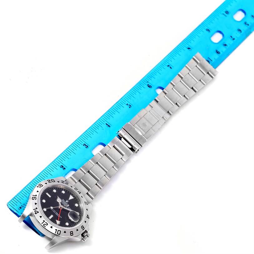 The image shows a top-down view of the Rolex Explorer 16570 Men's Stainless Steel Black Dial 16570 Men's Stainless Steel Black Dial watch, including its face, bezel, and metal bracelet, next to a ruler.