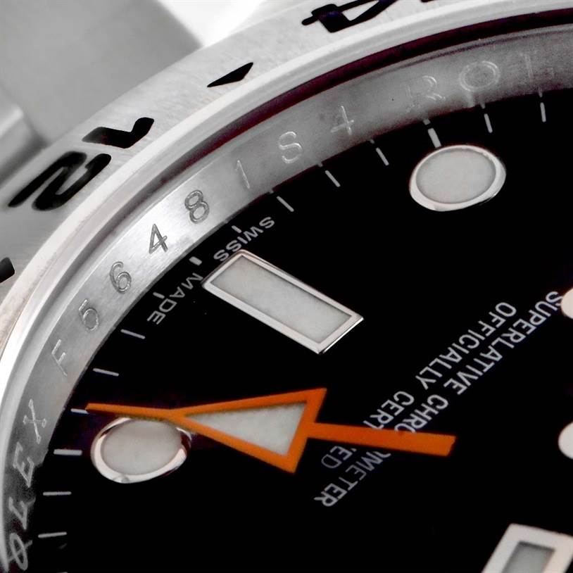 This image shows a close-up of the Rolex Explorer 216570 Men
s Stainless Steel Black Dial 216570 Men
s Stainless Steel Black Dial watch face, focusing on the dial, orange hand, and part of the bezel with markings.
