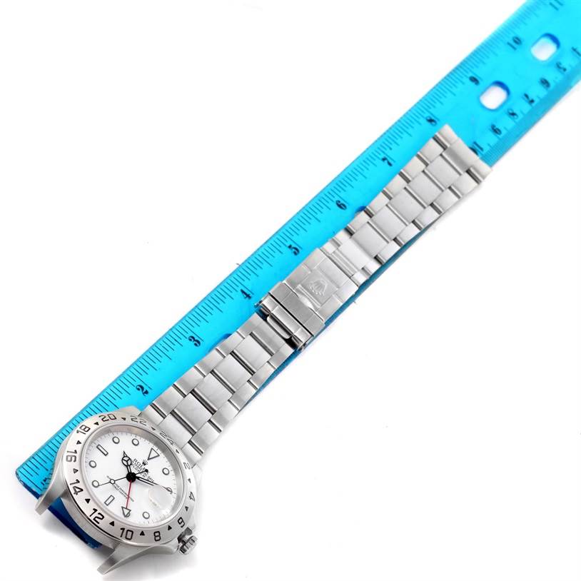 The Rolex Explorer 16570 Men's Stainless Steel White Dial 16570 Men's Stainless Steel White Dial watch is shown from an overhead angle, highlighting its face and metal band alongside a ruler for size comparison.