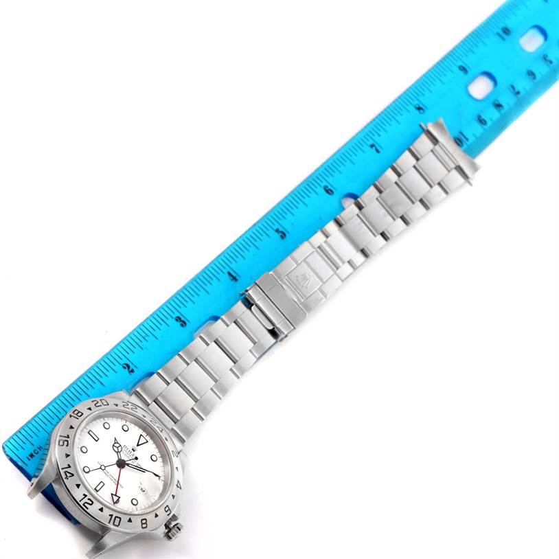 A Rolex Explorer 16570 Men's Stainless Steel White Dial 16570 Men's Stainless Steel White Dial watch is laid flat next to a blue ruler, showing the face, bezel, bracelet, and clasp.