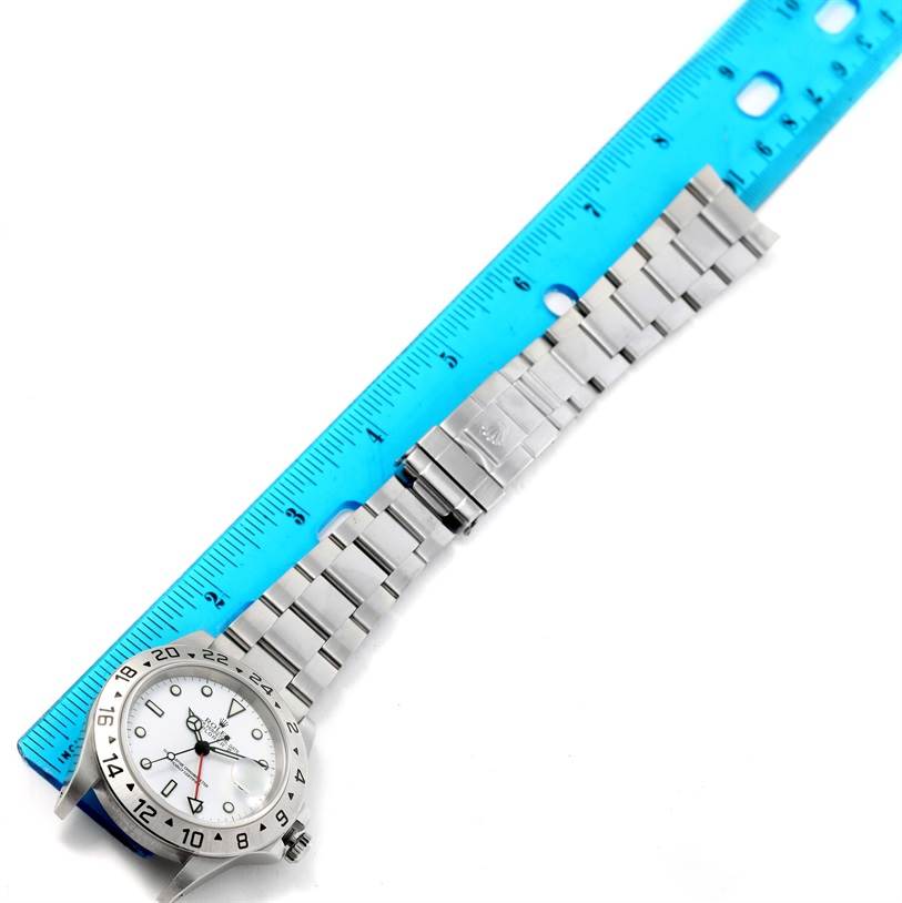 The image shows a top view of a Rolex Explorer 16570 Men's Stainless Steel White Dial 16570 Men's Stainless Steel White Dial model watch with a metal bracelet and a ruler for scale.