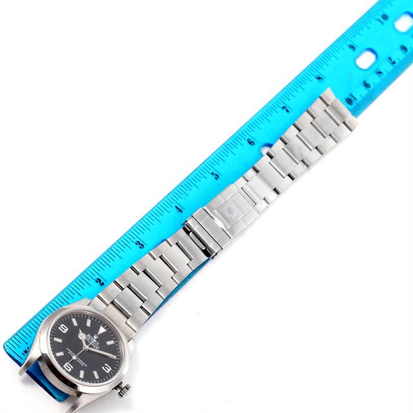 The image shows a top view of a Rolex Explorer 114270 Men's Stainless Steel Black Dial 114270 Men's Stainless Steel Black Dial watch and its full metal bracelet alongside a ruler for size reference.