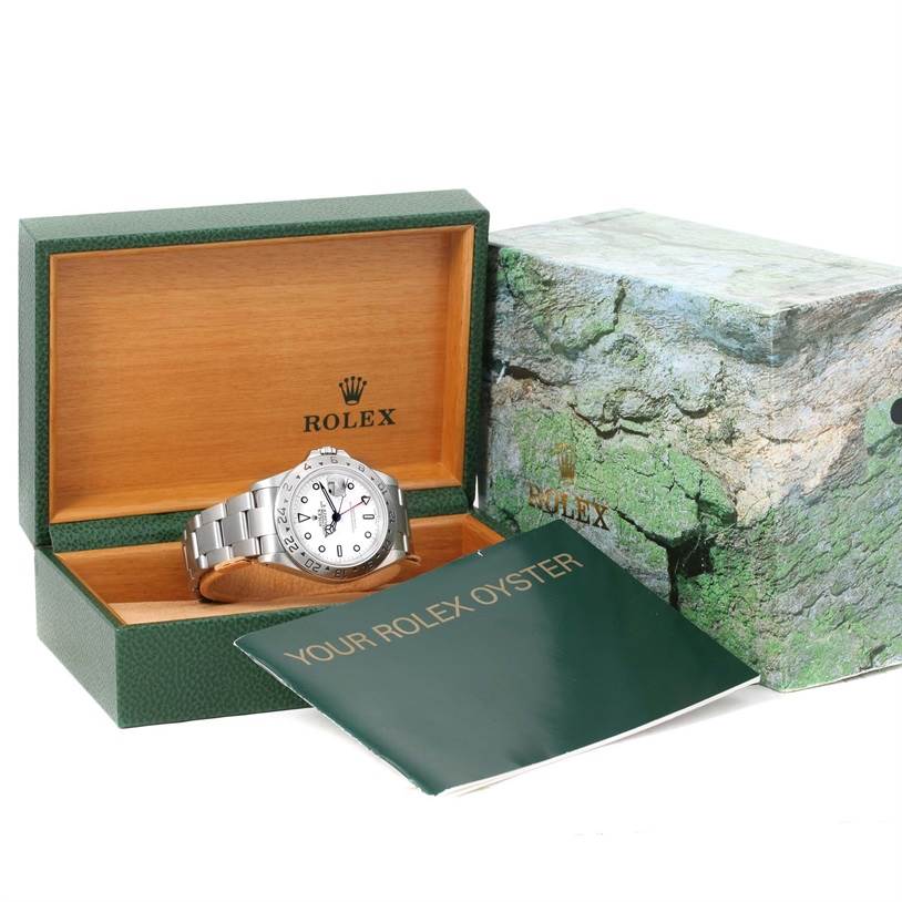 The image shows a Rolex Explorer 16570 Men's Stainless Steel White Dial 16570 Men's Stainless Steel White Dial watch placed in its open green and wooden box, with an outer box and booklet nearby.