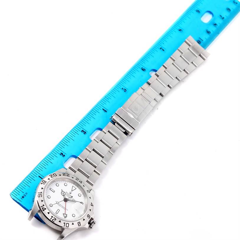 The image shows a Rolex Explorer 16570 Men's Stainless Steel White Dial 16570 Men's Stainless Steel White Dial watch laid flat next to a blue ruler, displaying the watch face and entire bracelet.