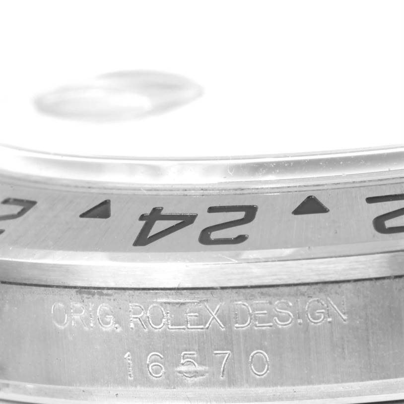 The image shows a close-up of the bezel and case of a Rolex Explorer 16570 Men's Stainless Steel White Dial 16570 Men's Stainless Steel White Dial model, focusing on the 24-hour markers and engraved text.