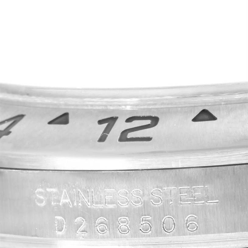 The image shows a close-up of the bezel and case of a Rolex Explorer 16570 Men's Stainless Steel White Dial 16570 Men's Stainless Steel White Dial watch, highlighting the engraved numbers and "Stainless Steel" inscription.