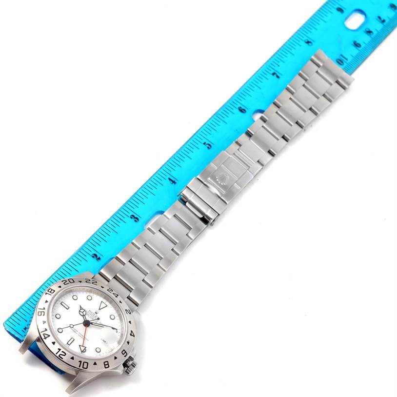 The Rolex Explorer 16570 Men's Stainless Steel White Dial 16570 Men's Stainless Steel White Dial watch is shown from a top-down angle, grouped with a metal bracelet and next to a ruler for size reference.