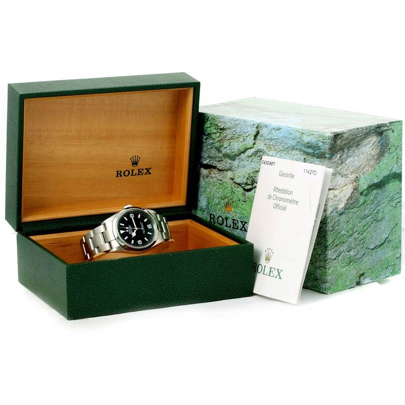 The image shows a Rolex Explorer 114270 Men's Stainless Steel Black Dial 114270 Men's Stainless Steel Black Dial watch in an open green and wooden box, with the outer box and papers visible.