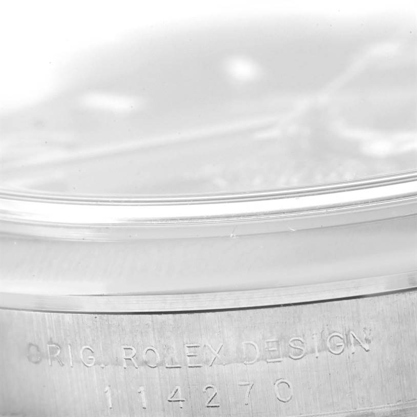 Close-up of the side of a Rolex Explorer 114270 Men
s Stainless Steel Black Dial 114270 Men
s Stainless Steel Black Dial watch case showing the engraved serial number and "ORIG. ROLEX DESIGN" inscription.