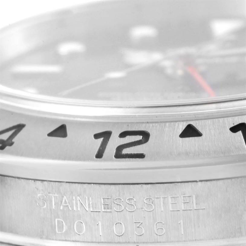 Close-up of the bezel and part of the dial of a Rolex Explorer 16570 Men's Stainless Steel Black Dial 16570 Men's Stainless Steel Black Dial watch, showing the "12" and "STAINLESS STEEL" engraving.