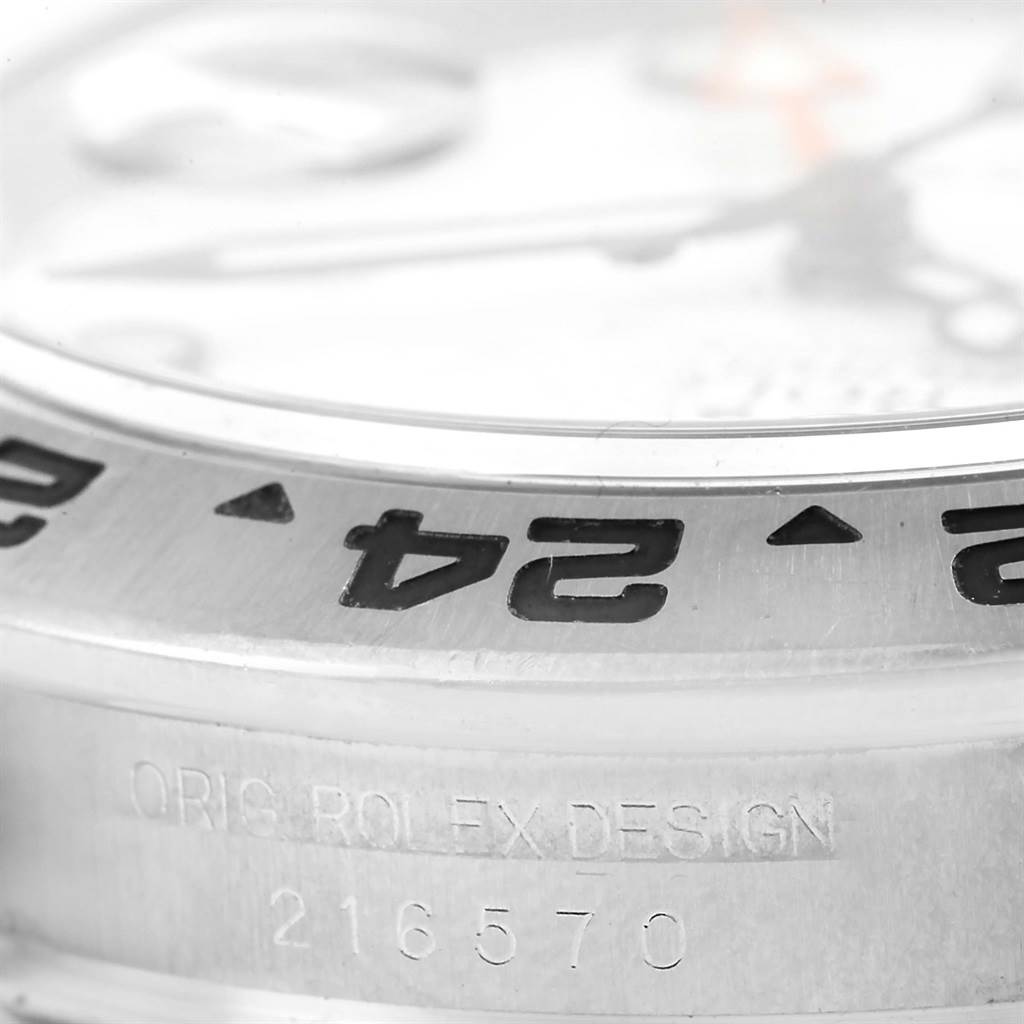 This image shows a close-up of the Rolex Explorer 216570 Men's Stainless Steel White Dial 216570 Men's Stainless Steel White Dial's bezel and part of the case, highlighting the engraved numerals and text.