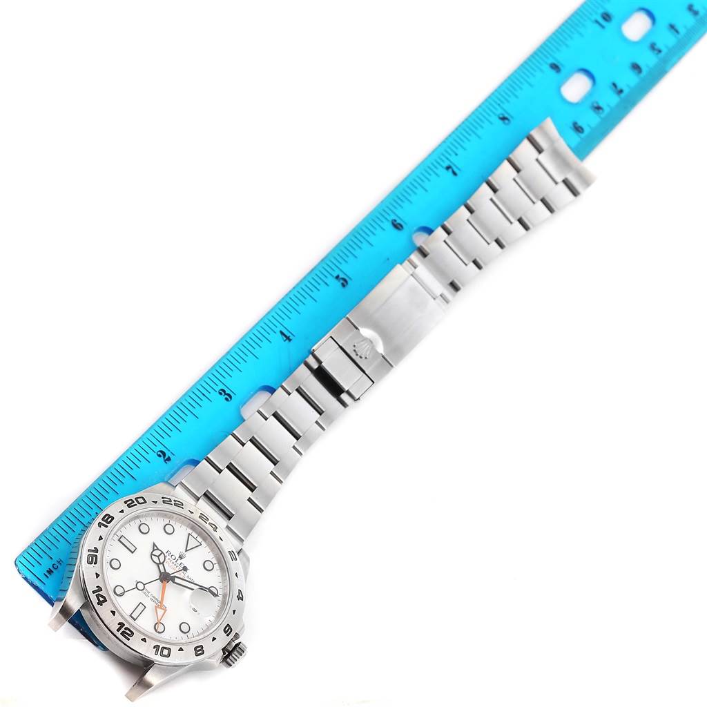 The image shows a full view of a Rolex Explorer 216570 Men's Stainless Steel White Dial 216570 Men's Stainless Steel White Dial watch, including its face, bezel, bracelet, and clasp, next to a blue ruler.