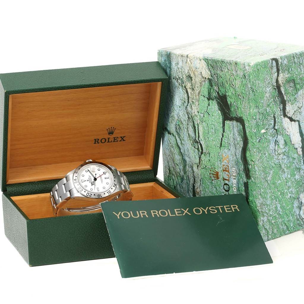 The image shows a Rolex Explorer 16570 Men
s Stainless Steel White Dial 16570 Men
s Stainless Steel White Dial model watch displayed in an open green and wooden Rolex box, alongside its original packaging and manual.