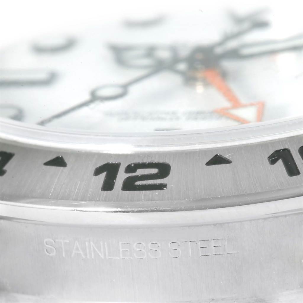 The image shows a close-up angled view of the bezel and part of the dial of the Rolex Explorer 216570 Men
s Stainless Steel White Dial 216570 Men
s Stainless Steel White Dial watch.
