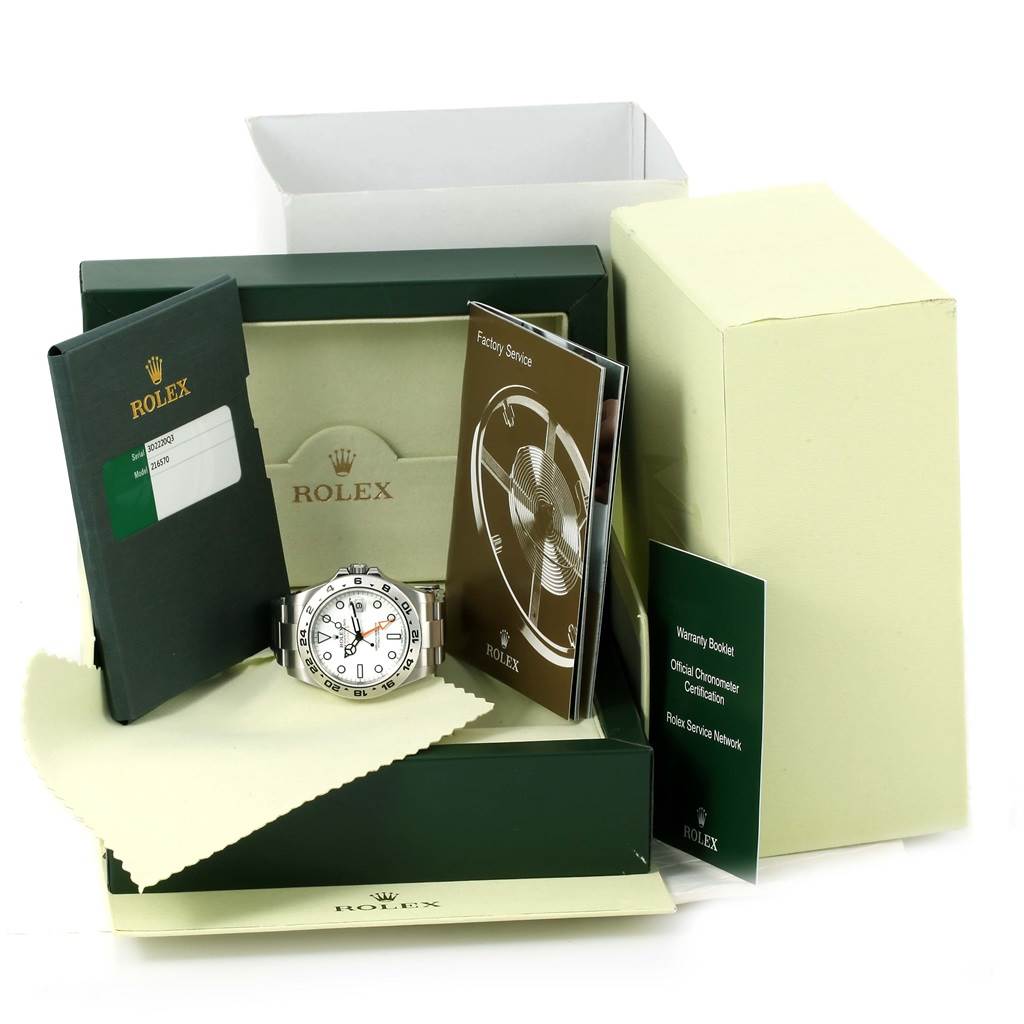 The image shows a Rolex Explorer 216570 Men
s Stainless Steel White Dial 216570 Men
s Stainless Steel White Dial watch with its box, warranty booklet, service booklet, and other related accessories from a front angle.