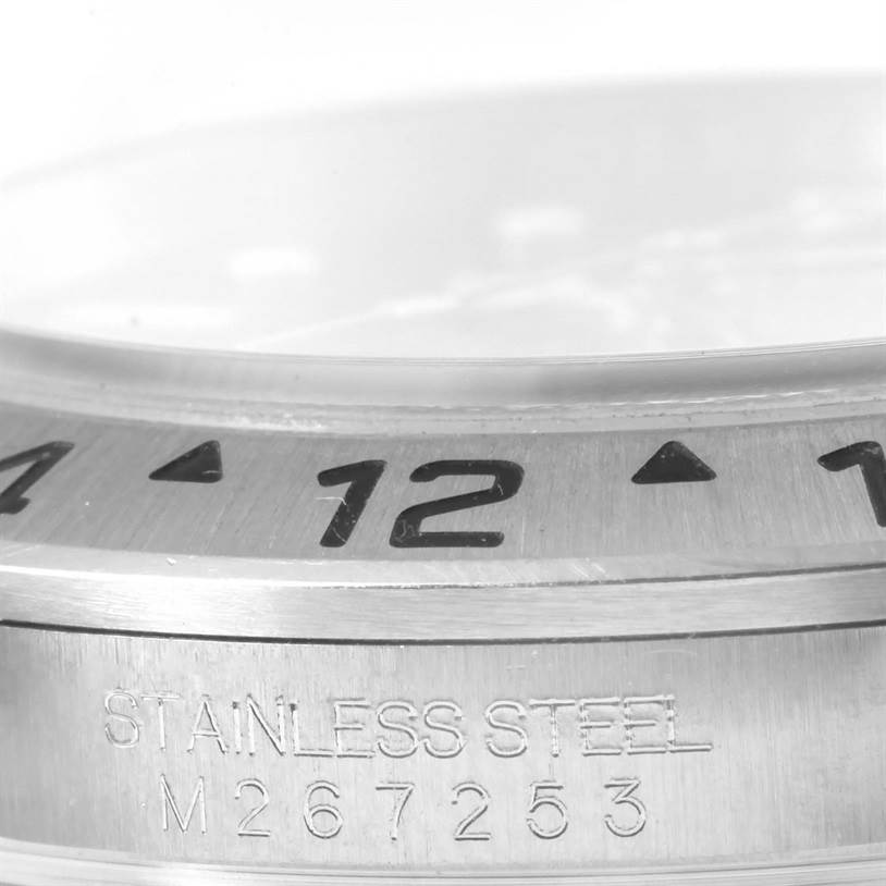 This close-up shows the bezel and stainless steel case of a Rolex Explorer 16570 Men's Stainless Steel Black Dial 16570 Men's Stainless Steel Black Dial model watch, displaying part of the 24-hour markers and serial number.