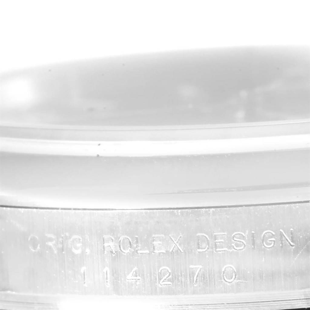 The image shows a close-up of the side of a Rolex Explorer 114270 Men's Stainless Steel Black Dial 114270 Men's Stainless Steel Black Dial watch, highlighting the engraving "ORIG. ROLEX DESIGN 114270".