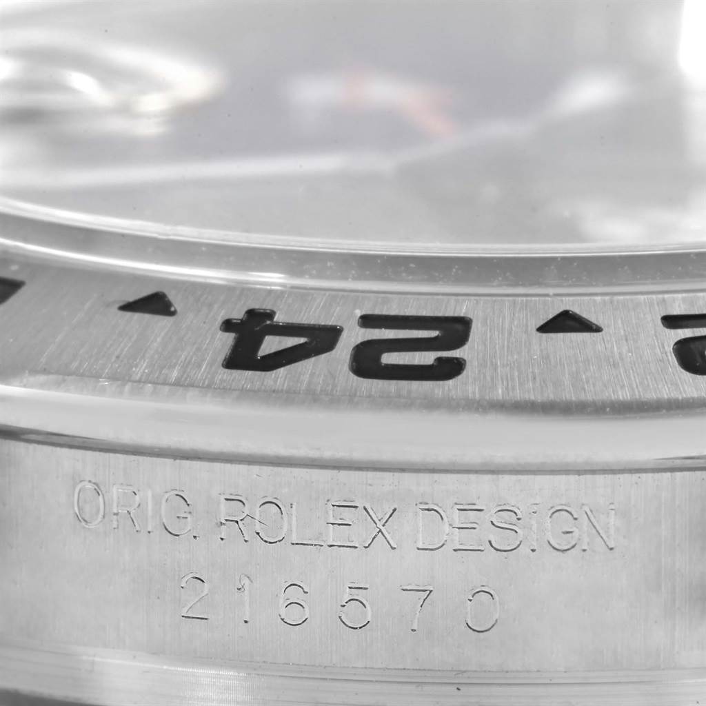 The image shows a close-up of the bezel and case of the Rolex Explorer 216570 Men
s Black Dial 216570 Men
s Black Dial model, highlighting the engraving and bezel markings.