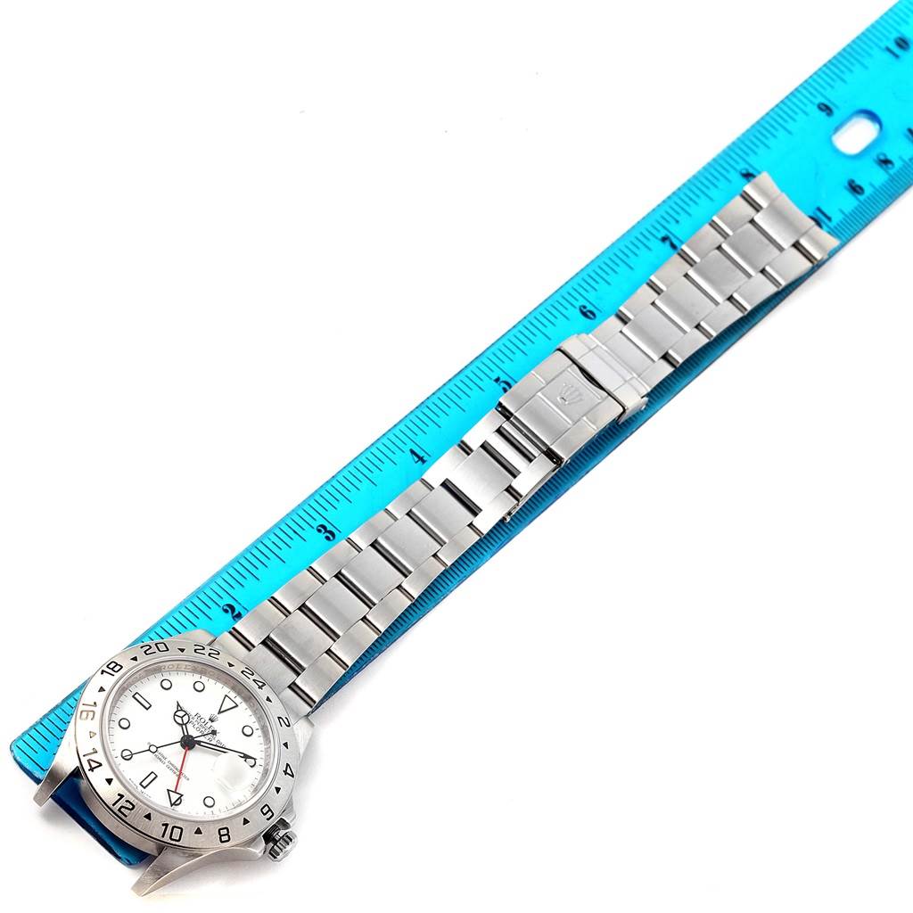 The Rolex Explorer 16570 Men's Stainless Steel White Dial 16570 Men's Stainless Steel White Dial watch is shown from a top-down angle alongside a blue ruler for scale.