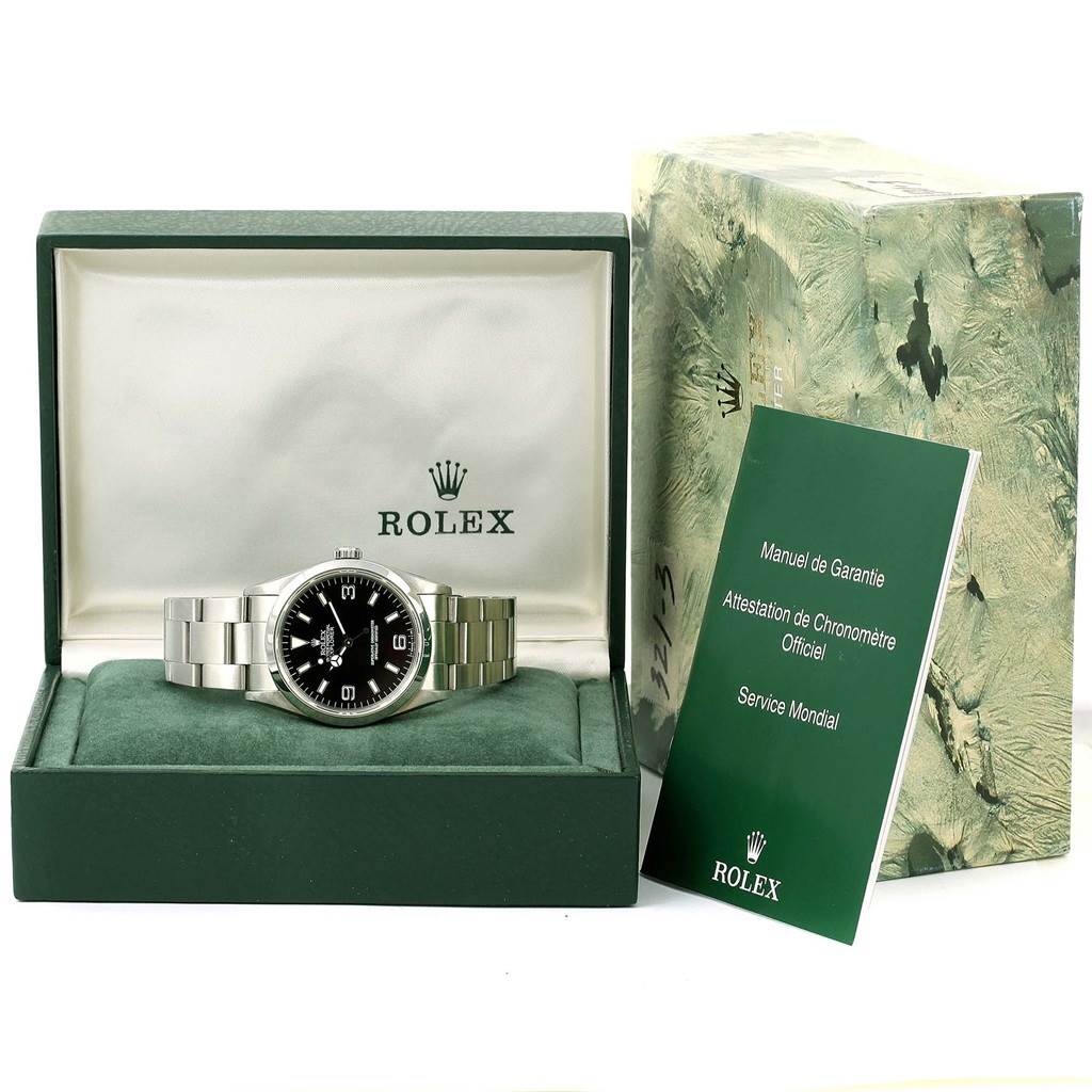 The Rolex Explorer 14270 Men
s Stainless Steel Black Dial 14270 Men
s Stainless Steel Black Dial watch is displayed front-facing in its green box, accompanied by a green manual booklet.