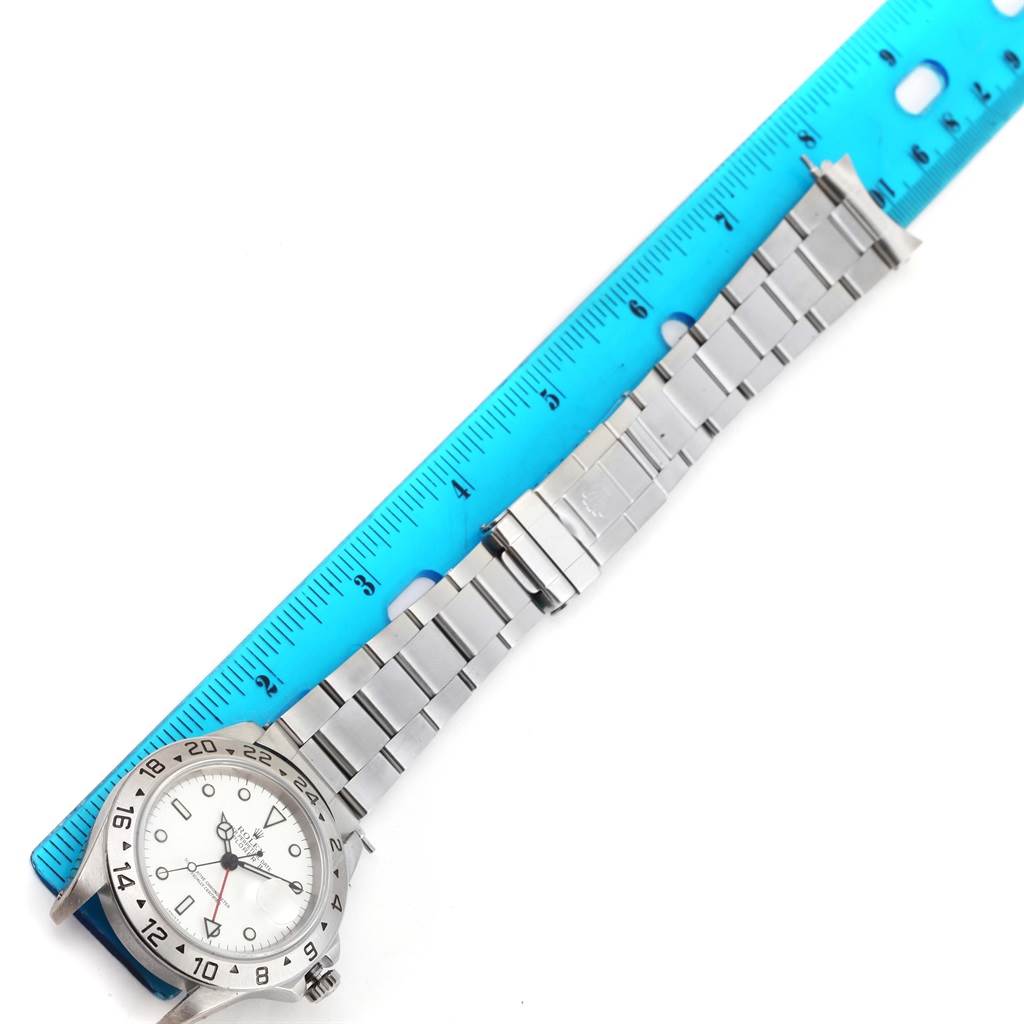 The image shows a horizontal view of a Rolex Explorer 16570 Men's Stainless Steel White Dial 16570 Men's Stainless Steel White Dial watch alongside a ruler, highlighting the watch face and metal bracelet.