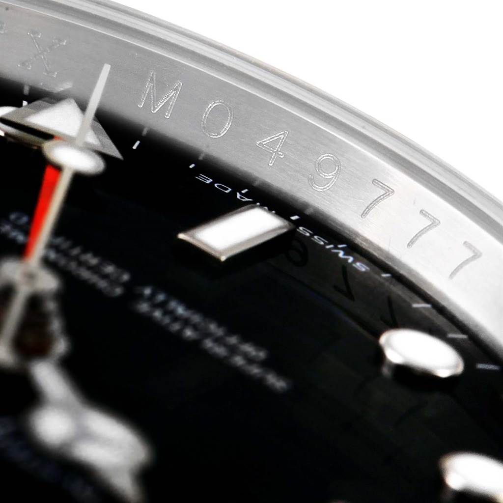 This close-up of a Rolex Explorer 16570 Men's Stainless Steel Black Dial 16570 Men's Stainless Steel Black Dial watch displays the serial number on the inner bezel and part of the dial with markers.