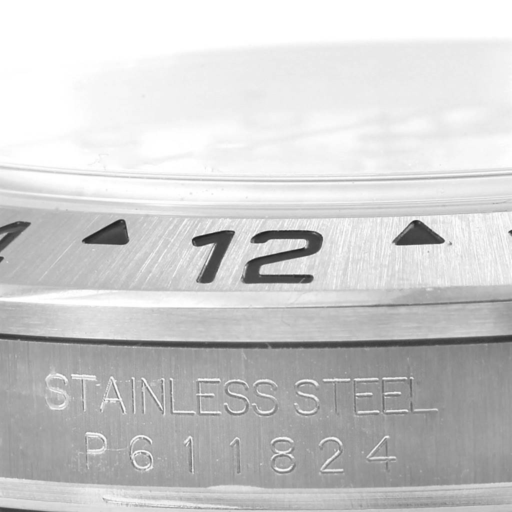 This close-up image of the Rolex Explorer 16570 Men's Stainless Steel White Dial 16570 Men's Stainless Steel White Dial model showcases the bezel, part of the crystal, and engraved stainless steel case.