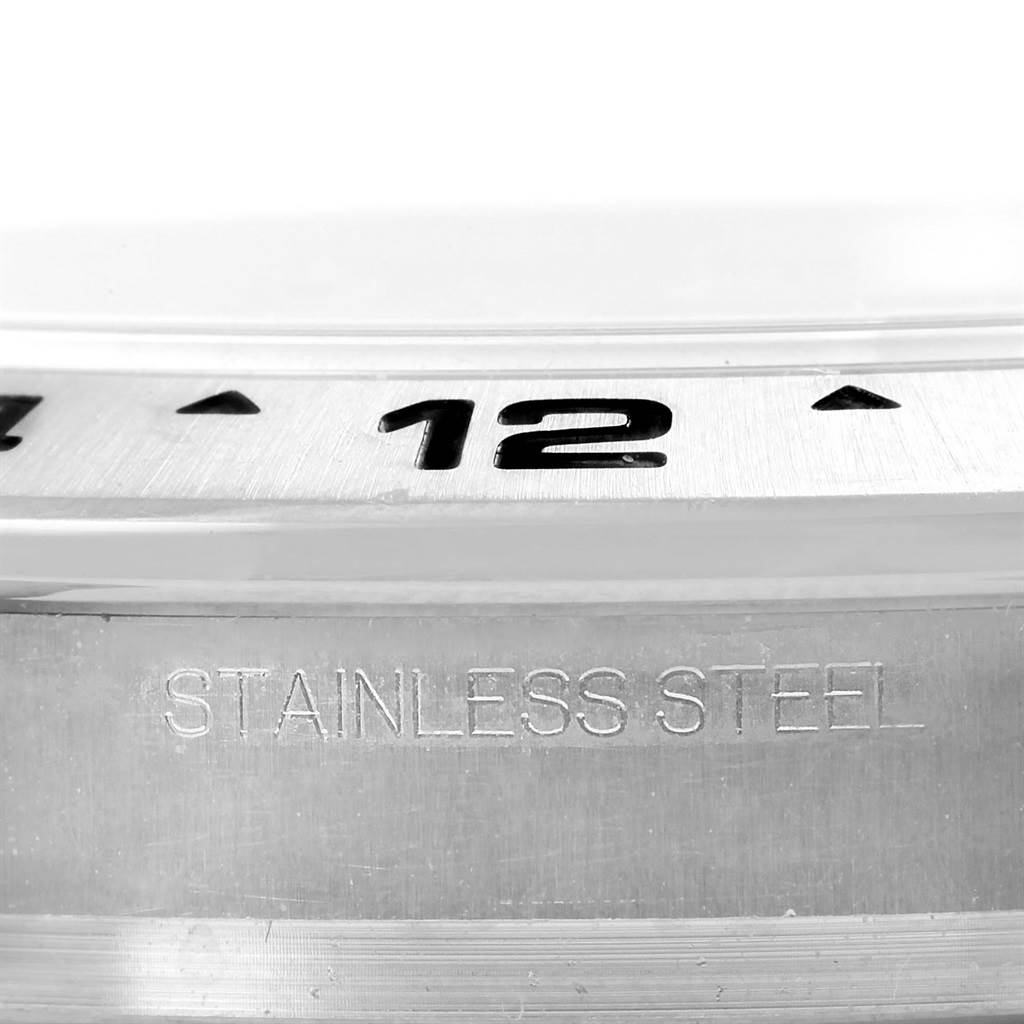 This image shows a close-up of the bezel and case of the Rolex Explorer 216570 Men
s Stainless Steel White Dial 216570 Men
s Stainless Steel White Dial watch, highlighting the "12" marker and "STAINLESS STEEL" engraving.