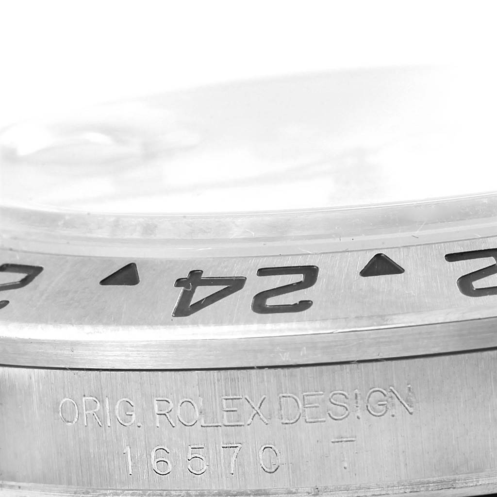 Close-up of the bezel and case engravings of a Rolex Explorer 16570 Men
s Stainless Steel White Dial 16570 Men
s Stainless Steel White Dial watch, showing "ORIG. ROLEX DESIGN" and model number "16570 T."
