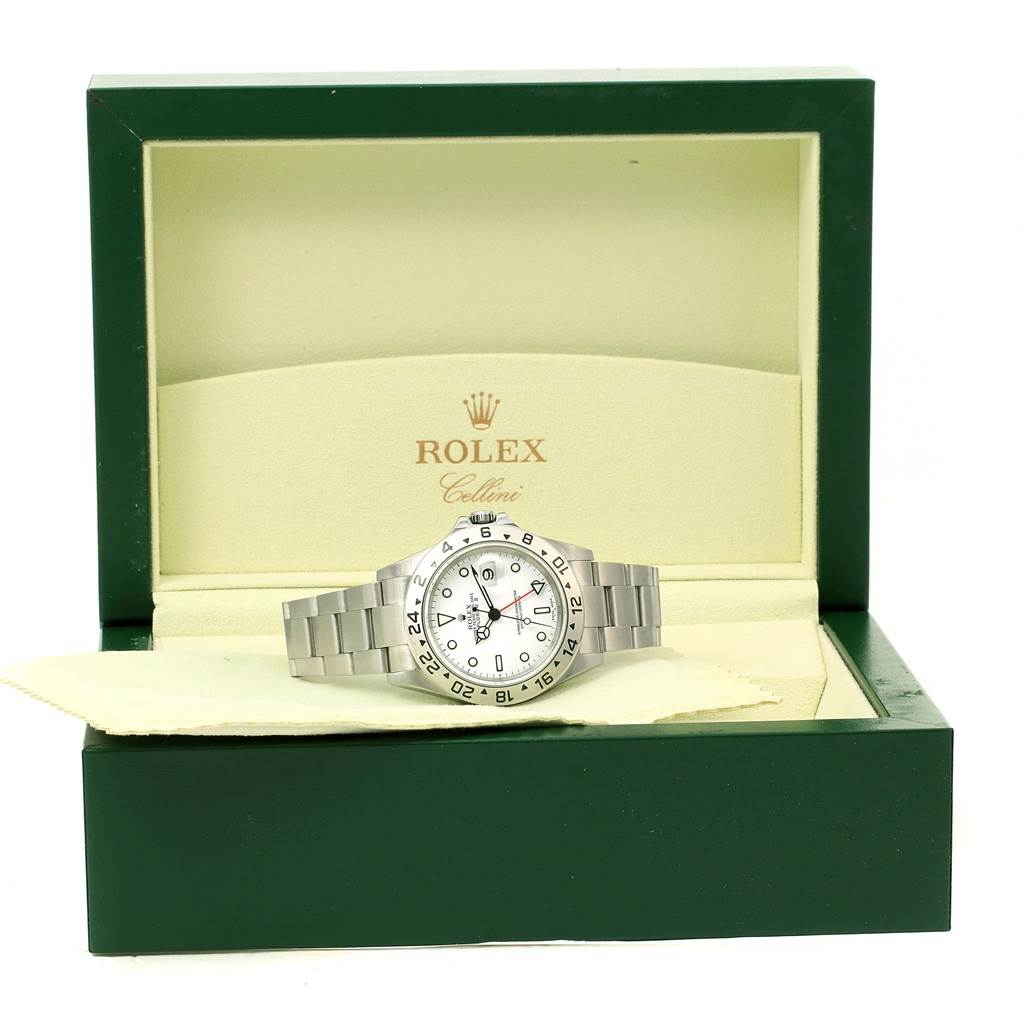 The Explorer model by Rolex is shown front-facing, displayed in its branded green and beige case.