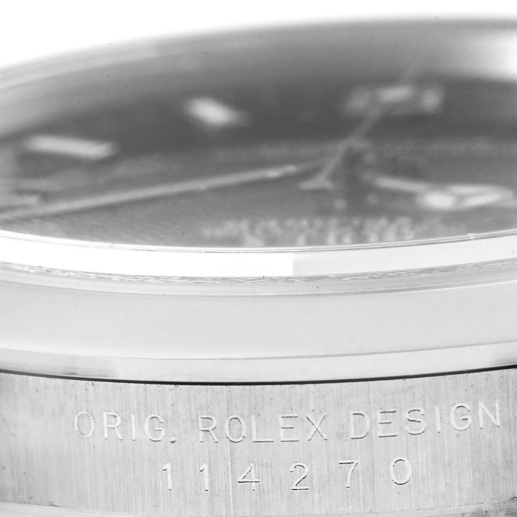 Close-up, angled view of a Rolex Explorer 114270 Men's Stainless Steel Black Dial 114270 Men's Stainless Steel Black Dial watch, showing the watch case and engraved "Orig. Rolex Design" with model number 114270.