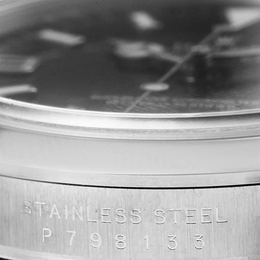 This close-up image of a Rolex Explorer 114270 Men's Stainless Steel Black Dial 114270 Men's Stainless Steel Black Dial watch shows part of the stainless steel case with an engraved serial number.