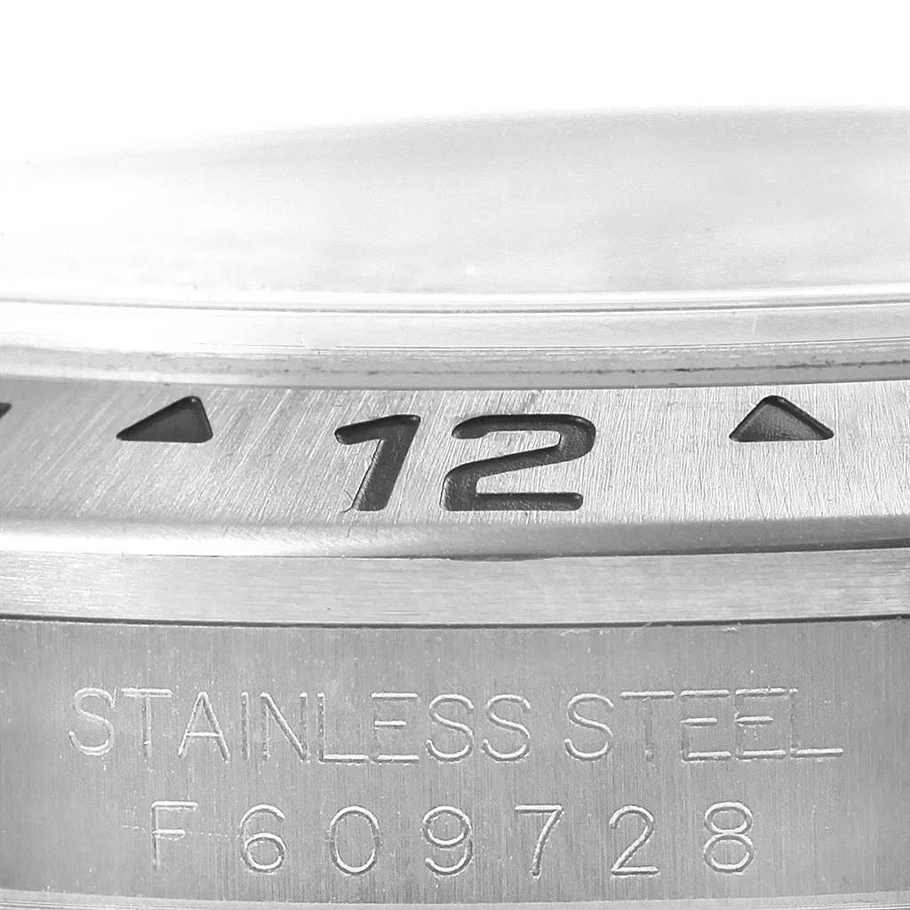 Close-up of a Rolex Explorer 16570 Men's Stainless Steel White Dial 16570 Men's Stainless Steel White Dial watch bezel and case, showcasing the "12" marker and "Stainless Steel" engraving.