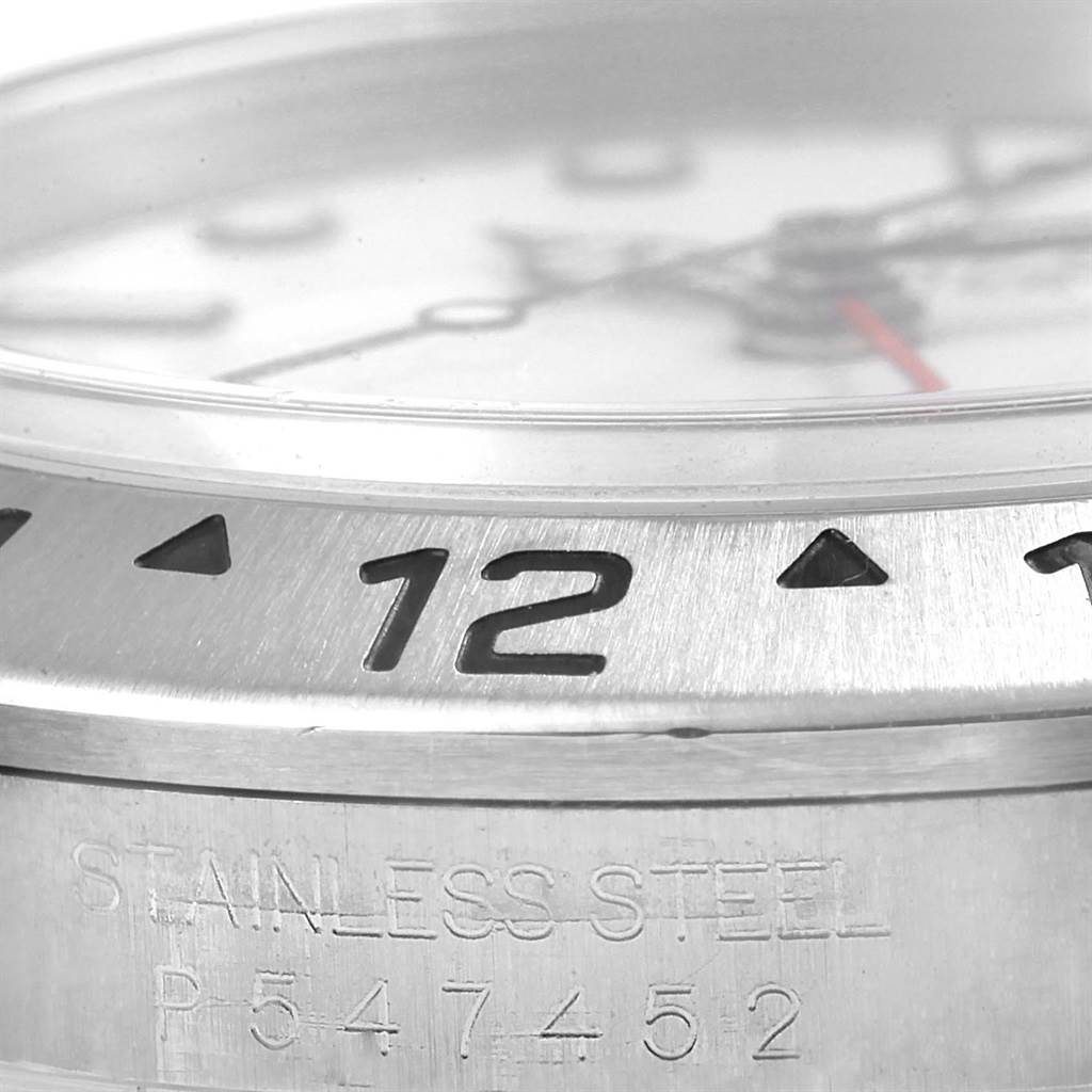 This close-up image of the Rolex Explorer 16570 Men's Stainless Steel White Dial 16570 Men's Stainless Steel White Dial watch shows the bezel and a portion of the stainless steel case with serial number.