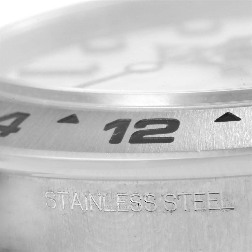 This close-up angle of the Rolex Explorer 216570 Men's Stainless Steel White Dial 216570 Men's Stainless Steel White Dial watch shows the bezel with engraved numbers and a "STAINLESS STEEL" marking.
