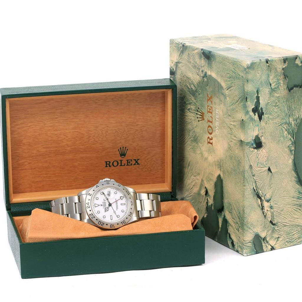The Rolex Explorer 16570 Men's Stainless Steel White Dial 16570 Men's Stainless Steel White Dial watch is displayed inside its box which is open near 90-degree angle, next to a decorative outer box.