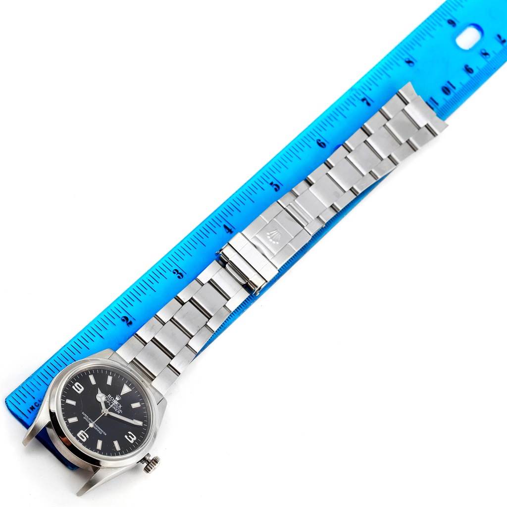 The image shows a Rolex Explorer 114270 Men's Stainless Steel Black Dial 114270 Men's Stainless Steel Black Dial watch laid flat next to a ruler, highlighting the watch case, dial, crown, and bracelet.