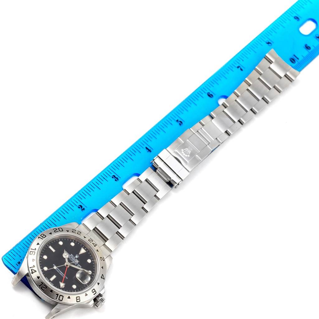 The image shows a Rolex Explorer 16570 Men's Stainless Steel Black Dial 16570 Men's Stainless Steel Black Dial watch laid flat, highlighting its bracelet, clasp, and part of the face, alongside a ruler.