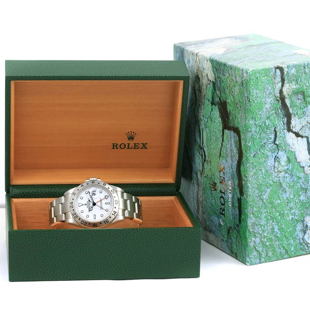 The Rolex Explorer 16570 Men's Stainless Steel White Dial 16570 Men's Stainless Steel White Dial watch is displayed head-on inside an open green and wooden box, with its packaging beside it.