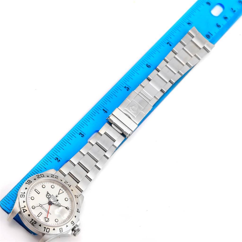 The Rolex Explorer 16570 Men's Stainless Steel White Dial 16570 Men's Stainless Steel White Dial watch is shown with its full stainless steel bracelet and clasp next to a blue ruler for scale.