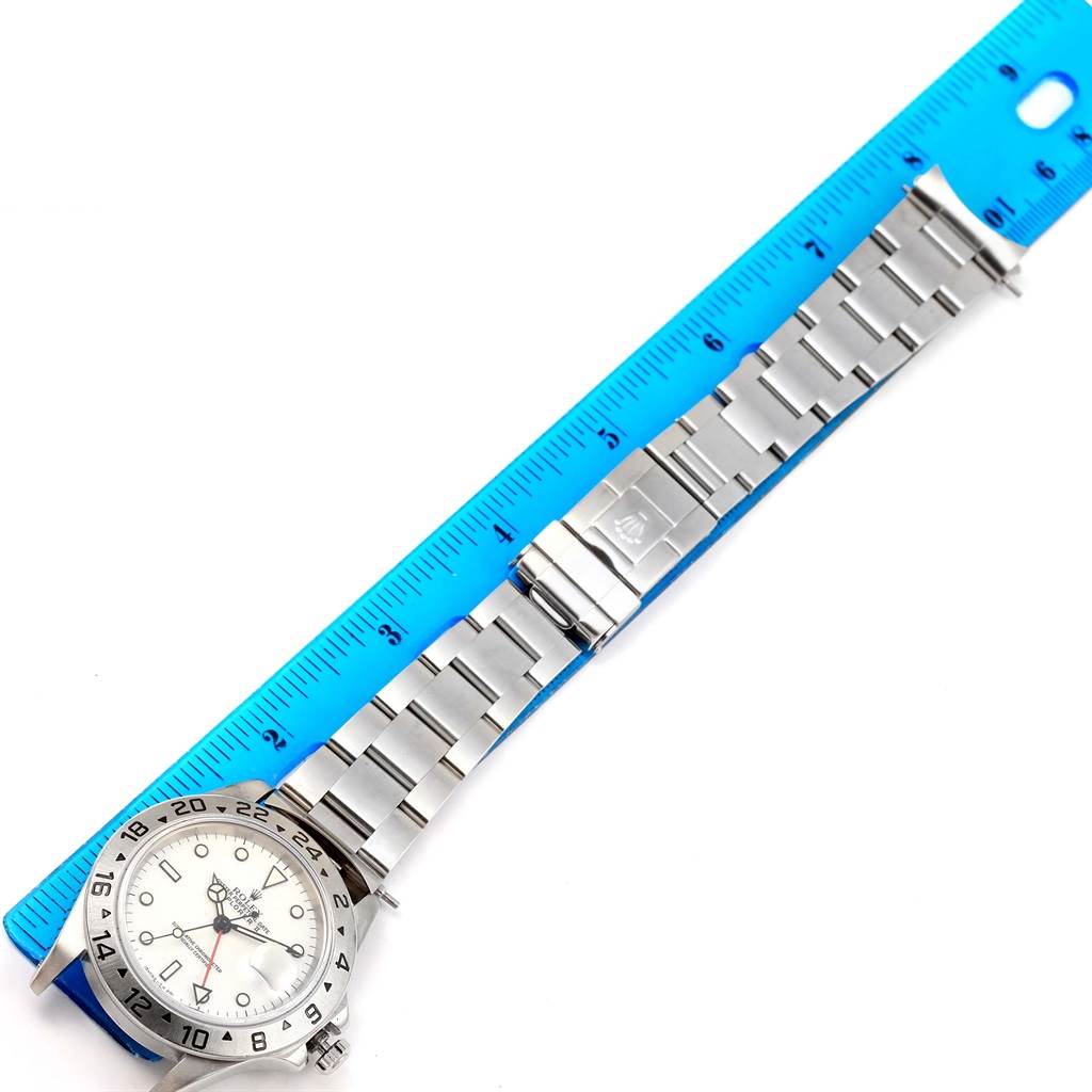 A Rolex Explorer 16570 Men's Stainless Steel White Dial 16570 Men's Stainless Steel White Dial watch is laid flat with its full bracelet visible next to a blue ruler for measurement.