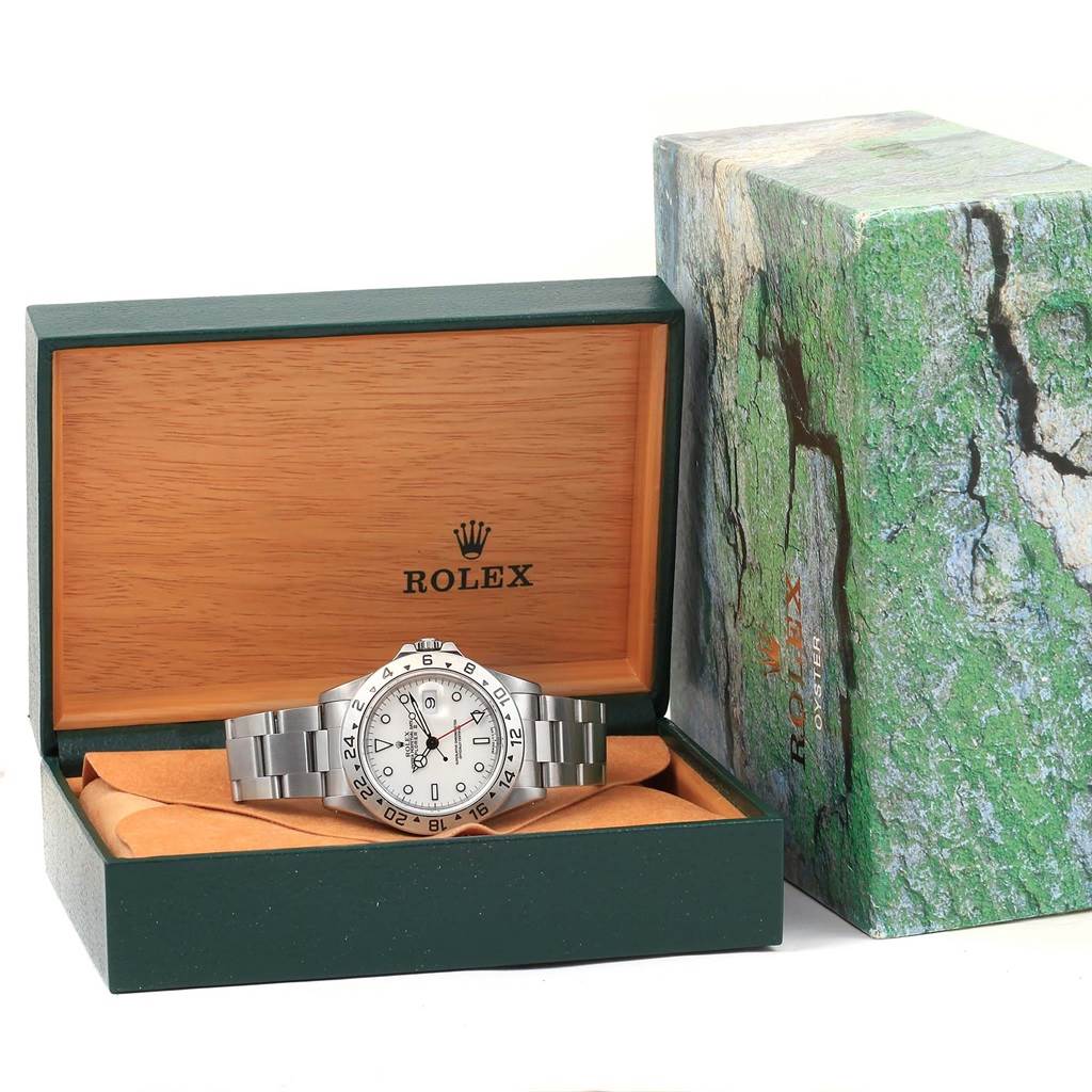 The Rolex Explorer 16570 Men's Stainless Steel White Dial 16570 Men's Stainless Steel White Dial watch is shown from a front angle inside its open green and wooden box, with the exterior box placed beside it.