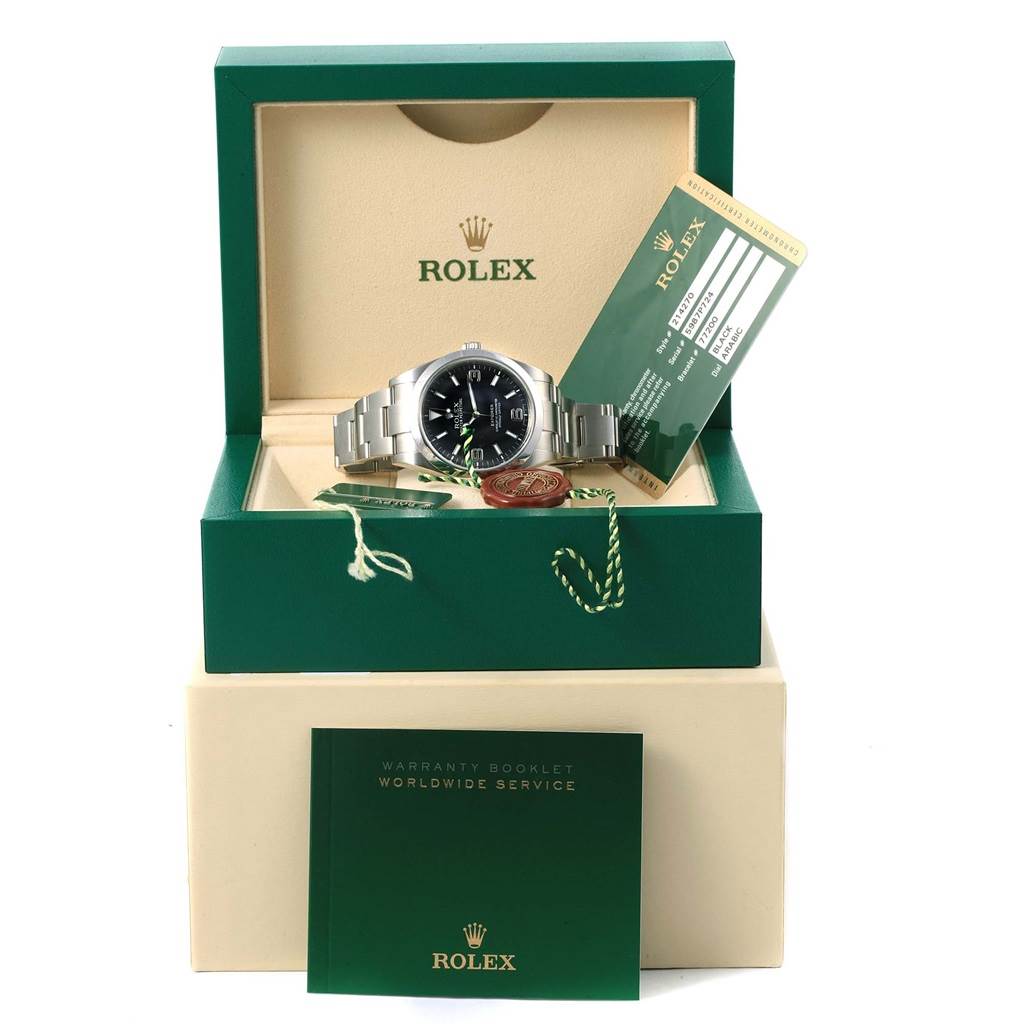 The Rolex Explorer 214270 Men's Stainless Steel Black Dial 214270 Men's Stainless Steel Black Dial watch is displayed in an open box with warranty cards and a booklet.