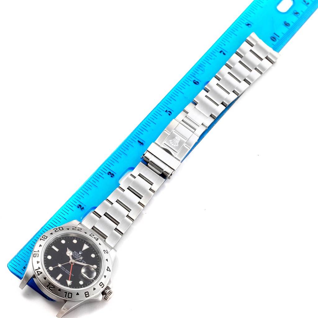 The image shows a Rolex Explorer 16570 Men's Stainless Steel Black Dial 16570 Men's Stainless Steel Black Dial watch laid flat next to a blue ruler, displaying the watch face and band.